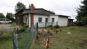 A white building with a brick chimney, surrounded by a chain-link fence. - Ferienhaus, Parmen bei Feldberg (Parmen)