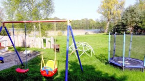 A playground with swings, a slide, and a trampoline.