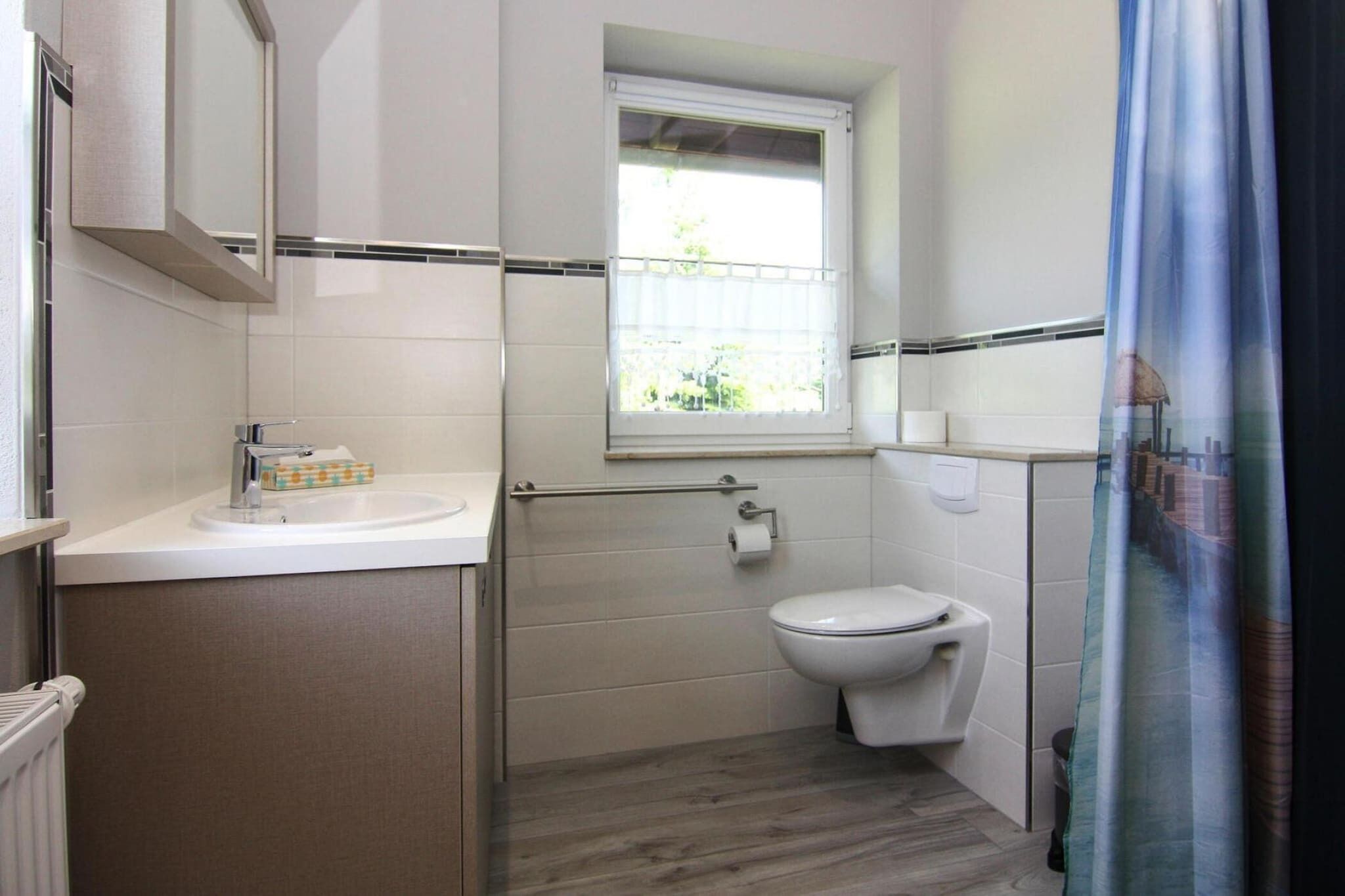 A bathroom with a toilet, a sink, a window, and a shower curtain.