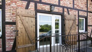 A wooden gate with a metal railing in front of a brick building with black beams.