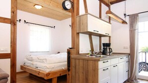 A compact room with a bed, a kitchenette, and a window.