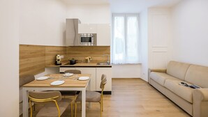 A modern kitchen with a dining area, a sofa, and a window. - 4 Stelle Housing - Rooms and Apartments by Wonderful Italy (Naples)