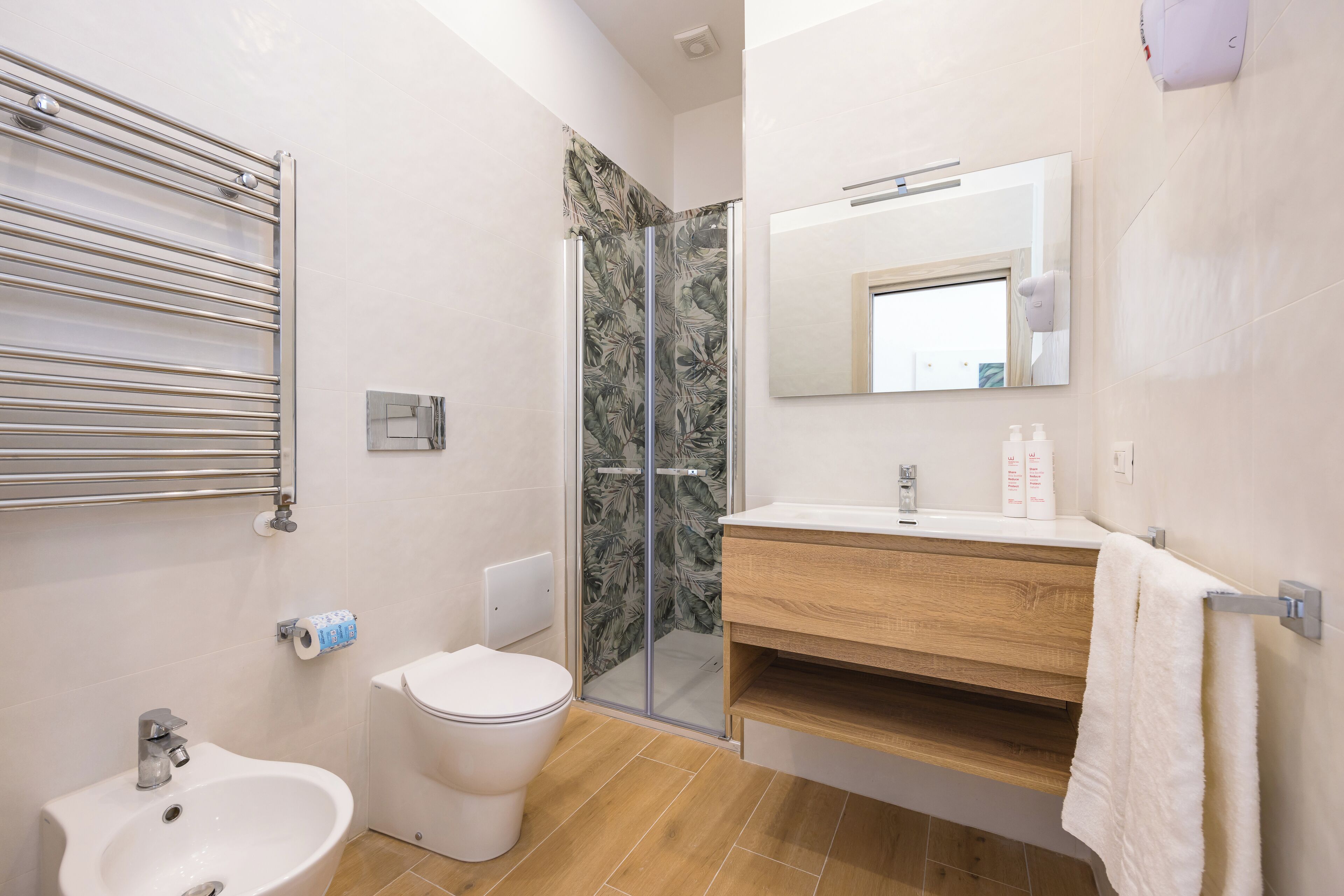 A modern bathroom with a glass shower enclosure, a wooden vanity, a white sink, and a toilet.