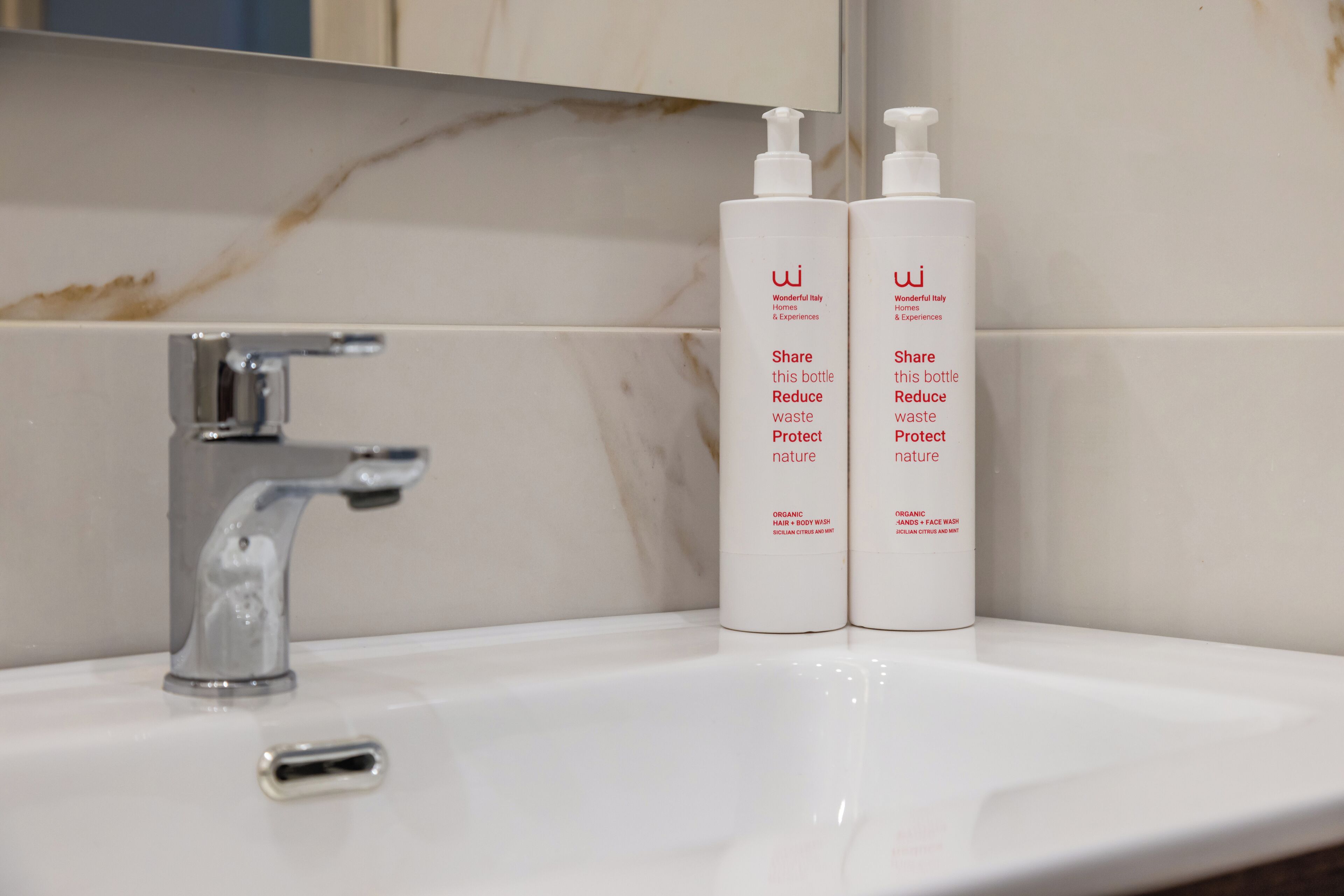Un lavabo de salle de bain avec deux flacons blancs de gel douche biologique et un robinet chromé.
