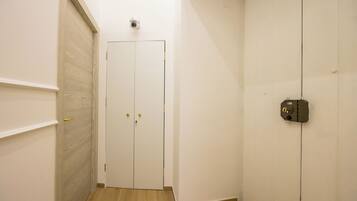A hallway with a closed door, a security camera, and a doorbell.