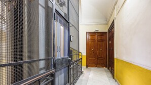 A hallway with a metal railing, a wooden door, and a yellow wall. - 4 Stelle Housing - Rooms and Apartments by Wonderful Italy (Naples)