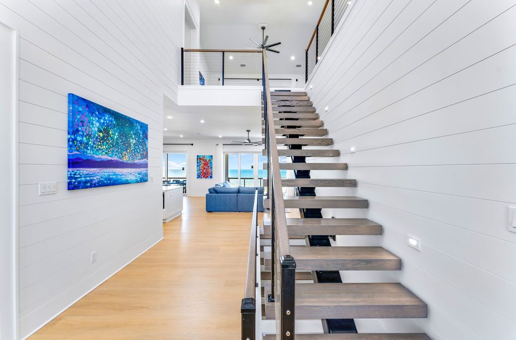 A modern interior with a wooden staircase, a dining area, and a view to the outside.