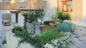 Edificio moderno con patio que tiene plantas en macetas y un banco de piedra.