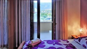 Una habitación de hotel con una cama, una mesita de noche, una lámpara y vistas al exterior.