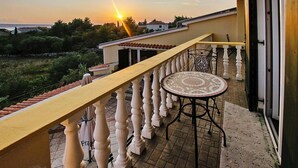 A balcony with a tiled floor, a round table with a patterned tablecloth, and a railing. - Villa in Starigrad near Paklenica National Park (Starigrad Paklenica)