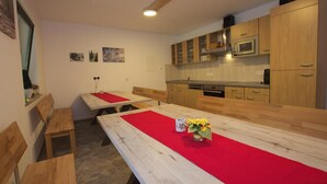 A dining area with wooden tables and benches, a red table runner, and a vase with flowers. - Ferienwohnung im Haus Schiefertal, Wieda (Wieda)