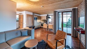 Un intérieur moderne avec un plafond en bois, un canapé, un coin repas et une cuisine.