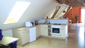 Une petite cuisine compacte, dotée d’appareils électroménagers de base, d’une fenêtre pour laisser entrer la lumière naturelle et d’une disposition simple.