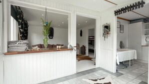 Une pièce avec un comptoir en bois, une plante suspendue, un tapis en peau de vache et un lit à baldaquin blanc.