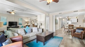 A spacious living room with a sofa, coffee table, and leather armchair. A dining area with a table and chairs is visible in the background. - Oceanfront Paradise Perfection 2BR Condo/ Balcony (North Myrtle Beach)