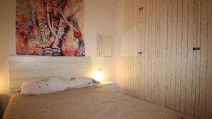 Ein Schlafzimmer mit einem großen Bett, einem Nachttisch, einer Wandlampe und einem Kleiderschrank.