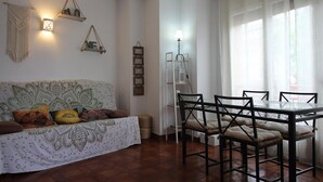 Ein Wohnzimmer mit einem gemusterten Sofa, einem Esstisch mit Stühlen und einem Deckenventilator.