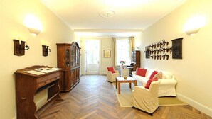 A spacious living room with a wooden herringbone floor, a white sofa set, a wooden cabinet, and wall-mounted animal horns. - Gutshaus Zicker in Garz (Garz)