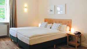 A double bed with a wooden headboard, two bedside lamps, and a bedside phone. - Gutshaus Zicker in Garz (Garz)