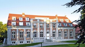 A large, historic building with a symmetrical facade, multiple windows, and a central entrance with steps leading up to it. - Gutshaus Zicker in Garz (Garz)