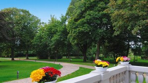 A garden with a paved walkway and white planters with flowers. - Gutshaus Zicker in Garz (Garz)