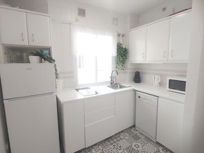 A kitchen with white cabinets, a sink, a microwave, and a dishwasher.