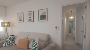 Een woonkamer met een bank, een lamp en drie kunstwerken in lijsten aan de muur.