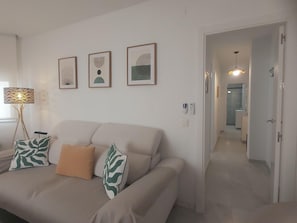 A living room with a sofa, a lamp, and three framed artworks on the wall.