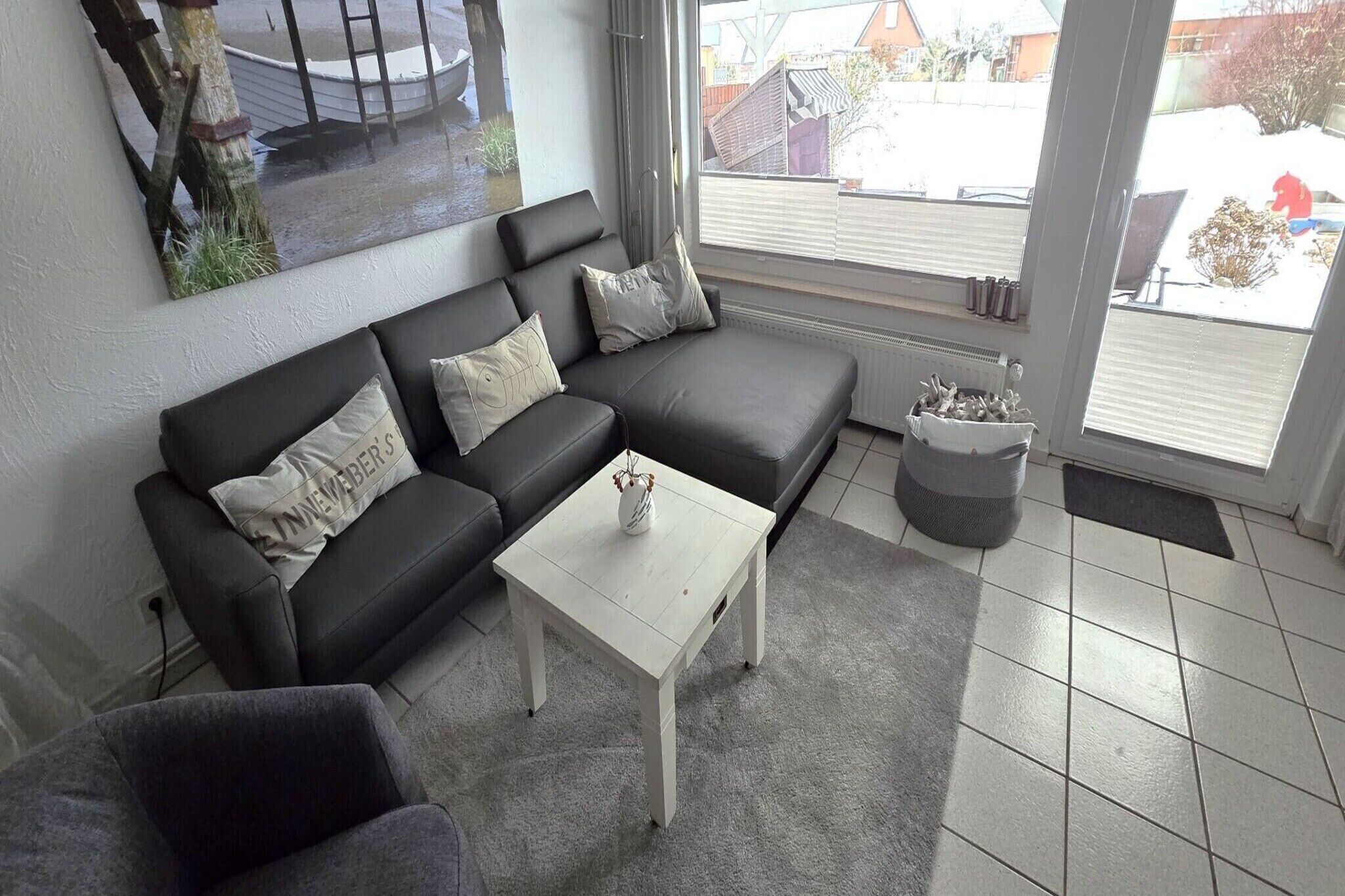 Ein Wohnzimmer mit einem schwarzen Ecksofa, einem weißen Couchtisch und einem grauen Teppich.