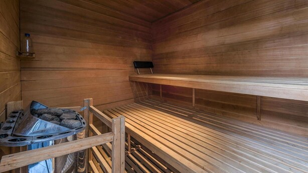 A sauna with wooden benches, a bench heater, and a bench for resting.