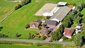 Eine Vogelperspektive eines ländlichen Anwesens mit mehreren Gebäuden, einem großen Feld und einer Straße.