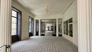 A spacious hallway with patterned floor tiles, large windows, and a chandelier. - Beautiful T3 apartment with terrace and Wi-Fi in the center of La Bourboule (La Bourboule)