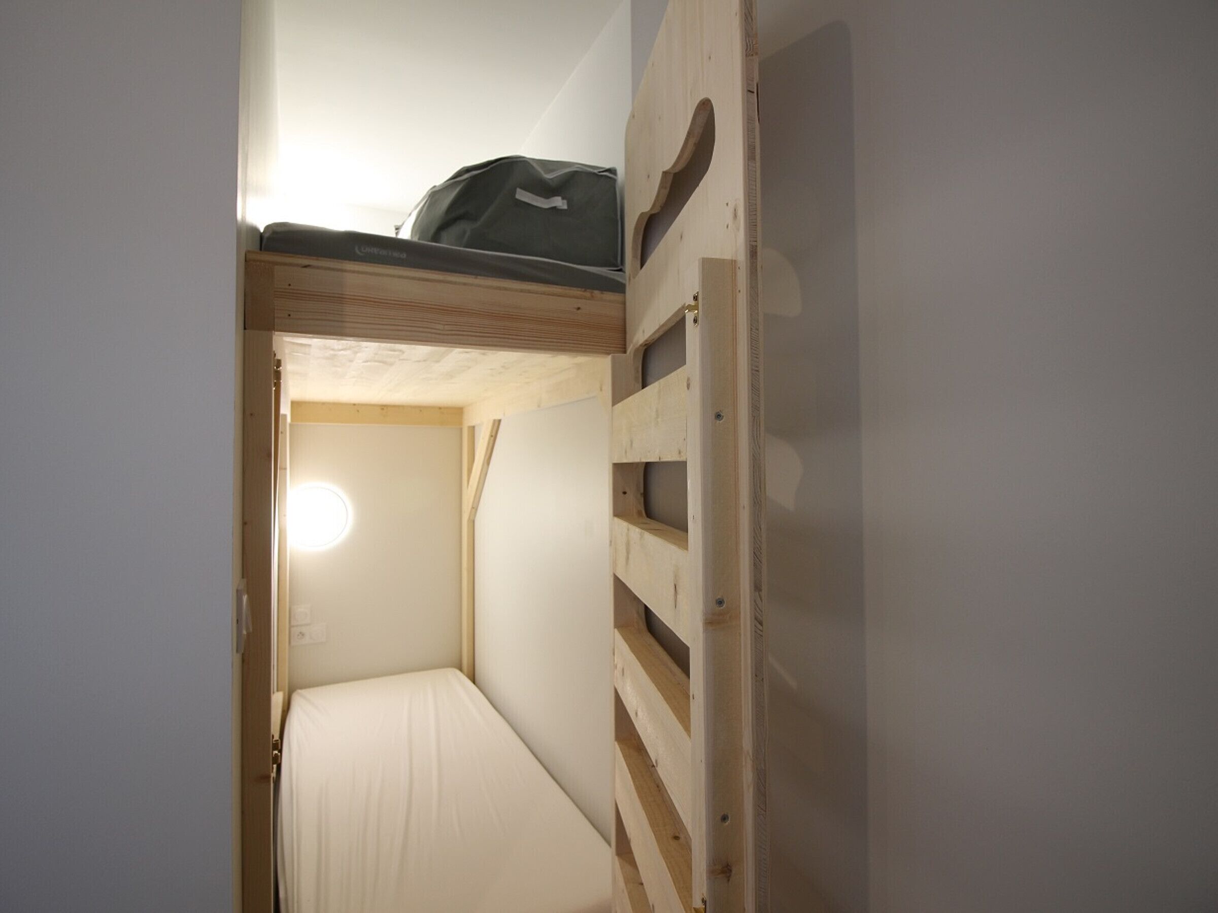 A bunk bed with a headboard and a small window.