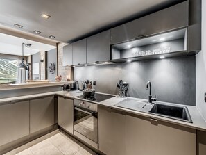 A modern kitchen with built-in appliances, a stainless steel sink, and a window overlooking a scenic view. - Tignes: 4* Apartment with South Balcony, 50m2, 2 Bdr, WiFi (Tignes)
