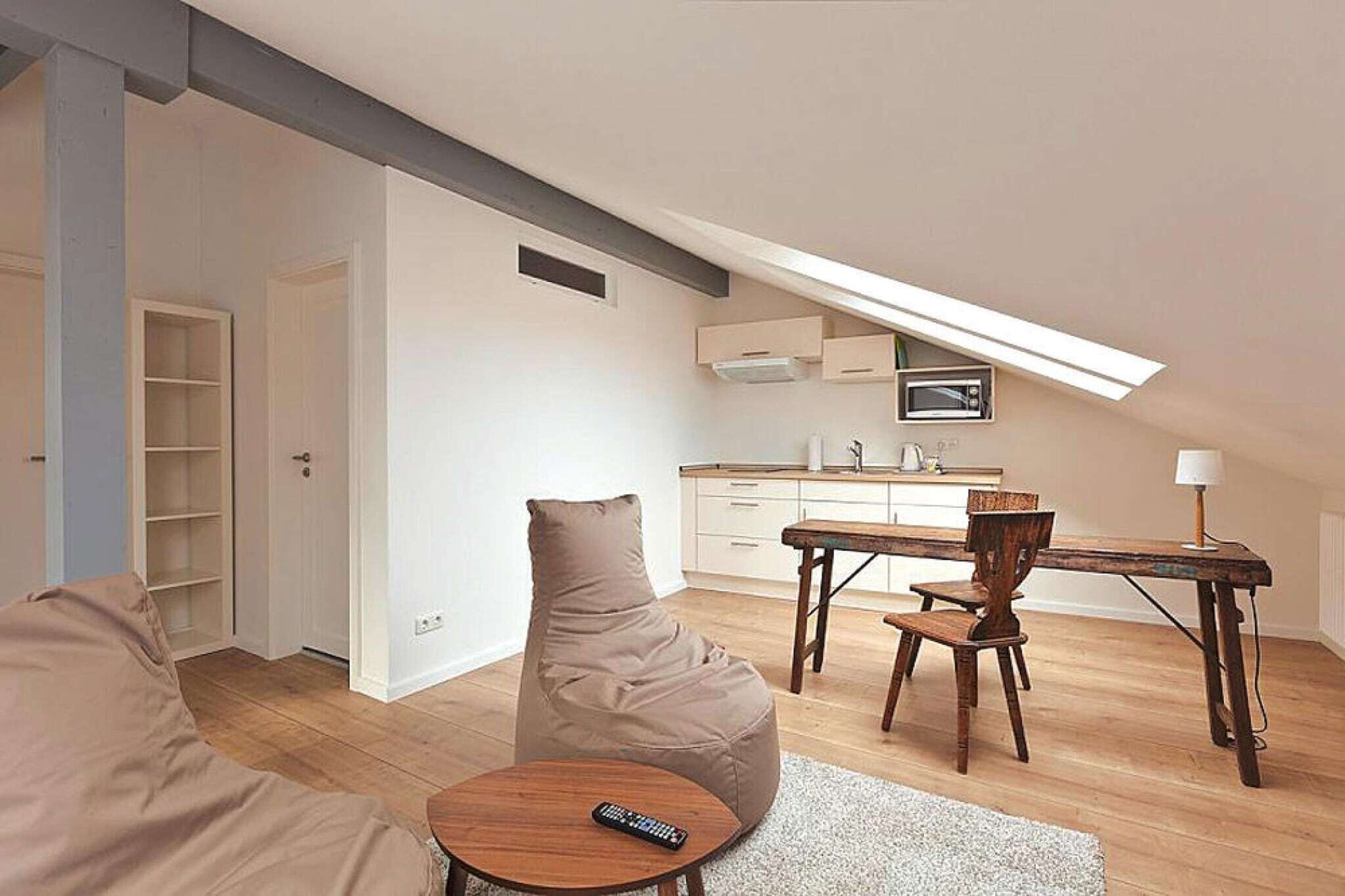 A modern loft apartment with a dining area, kitchenette, and a cozy seating area with a bean bag.