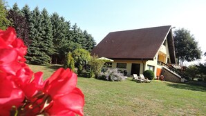 A house with a sloped roof, a front porch, and a small garden area with a bench and potted plants. - Holiday Home Sulomino with Private Beach (Sulomino)