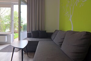 A modern living room with a grey sofa, a small table, and a green accent wall.
