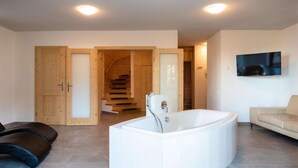 Ein modernes Badezimmer mit einer freistehenden Badewanne, Holztüren, einer Treppe und einem beigefarbenen Sofa.