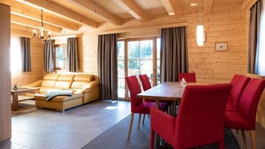 Ein Holzinterieur mit einer Couch, roten Stühlen und einem Esstisch.