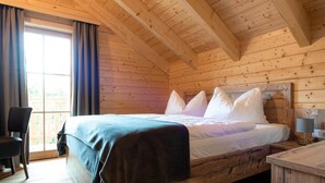 Ein Holzhüttenraum mit einem Bett, einem Sessel und einem Schreibtisch.