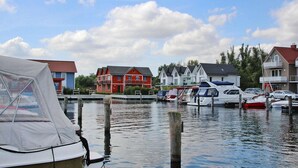 Un port de plaisance avec des bateaux amarrés, une rangée de maisons aux couleurs vives et un ciel dégagé.