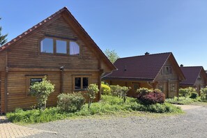 A wooden cabin with a sloped roof, a window with curtains, and a small garden in front. - Blockhaus, Bad Sachsa (Bad Sachsa)