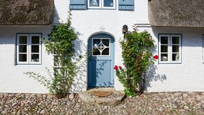 A white building with a blue door, shutters, and a stone foundation.