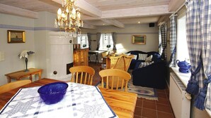 A dining area with a table, chairs, a chandelier, and a view of the living room.