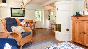 A living room with a wicker chair, a blue sofa, a wooden cabinet, and a dining area with a table and chairs.