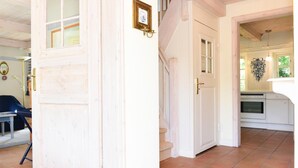 A white door with a small picture frame, a staircase, and a kitchen area with a stove.