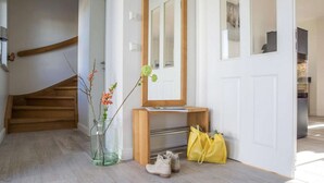 En trappa som leder upp till en liten plattform med en träbänk, en spegel, en vas med blommor och en gul väska på golvet.