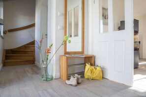 A staircase leading to a landing with a wooden bench, a mirror, a vase with flowers, and a yellow bag on the floor. - Reetdachhaus am Bodden mit Sauna (Fuhlendorf)
