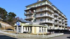 A multi-story residential building with balconies, a parking sign, and a white picket fence. - Apartment in Ustka near Baltic Sea Beach (Ustka)