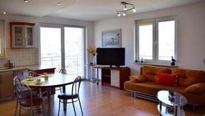 A modern apartment with a dining area, a living room with a sofa and TV, and large windows. - Apartment in Ustka near Baltic Sea Beach (Ustka)